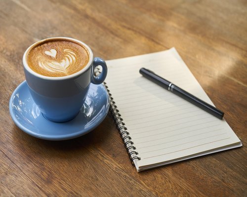 A quiet corner in a Mexican cafe with a notebook, pen, and a cup of coffee on a wooden table